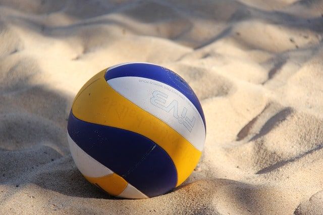 Yellow, white and blue volleyball in sand